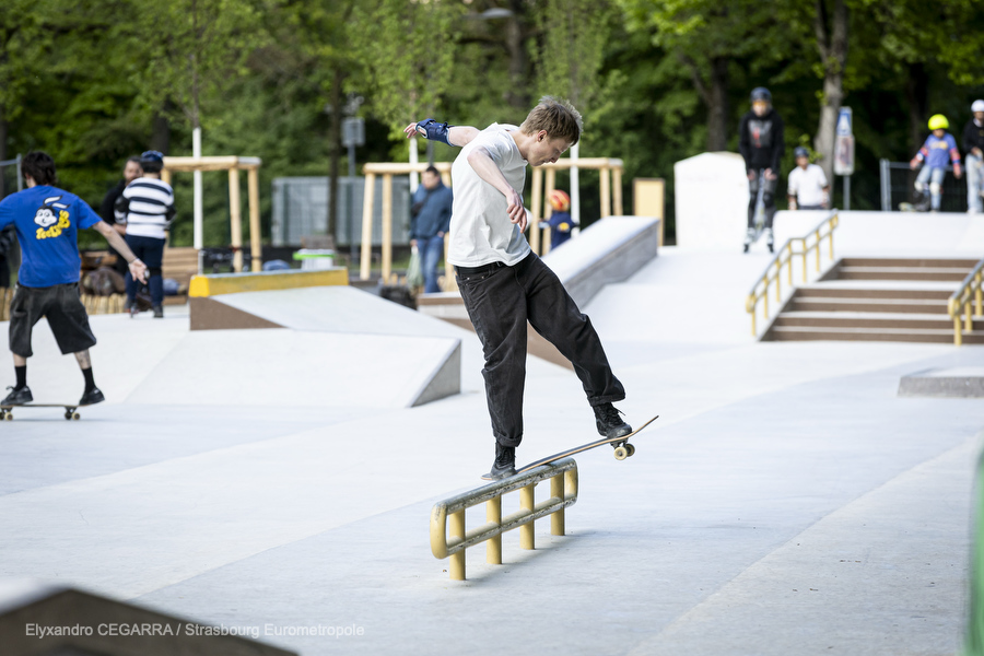 On voit un skater slider sur une rampe jaune