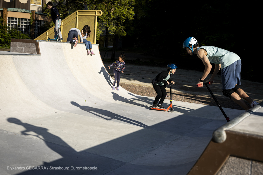 Vue sur la minirampe du skatepark, des enfants en trottinette descendent la rampe
