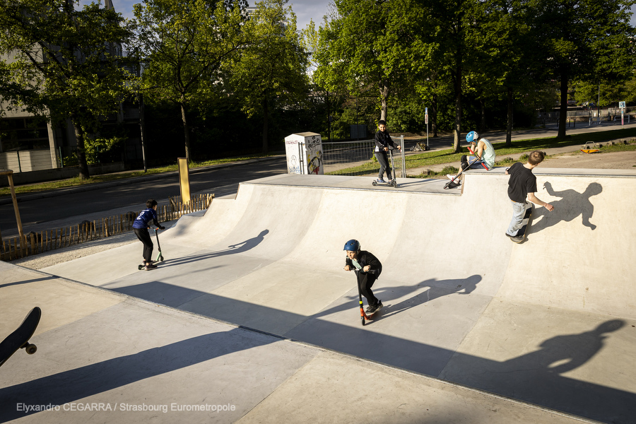 Vue sur la minirampe du skatepark, des enfants en trottinette descendent la rampe
